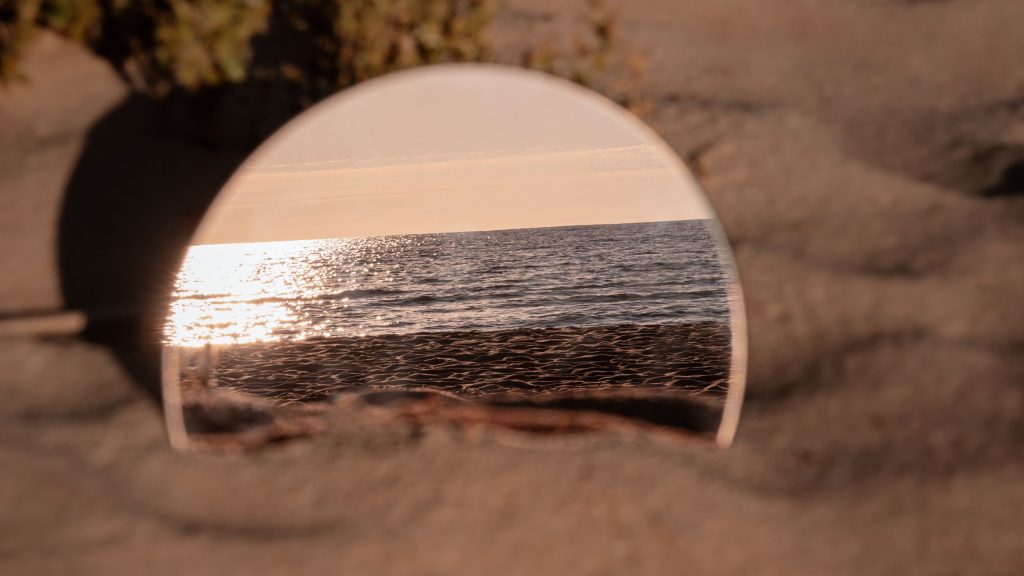 a mirror reflecting the sea on the beach